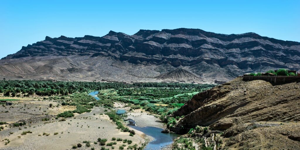 Stunning view of the rugged mountains and lush valley in Zagora, Morocco, under a clear blue sky.