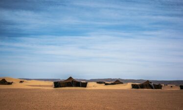 Majestic view of tents in the desert landscape of Zagora, Morocco with a clear blue sky.