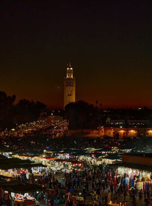 Experience the bustling night market in Marrakesh, Morocco, illuminated against a stunning twilight sky.