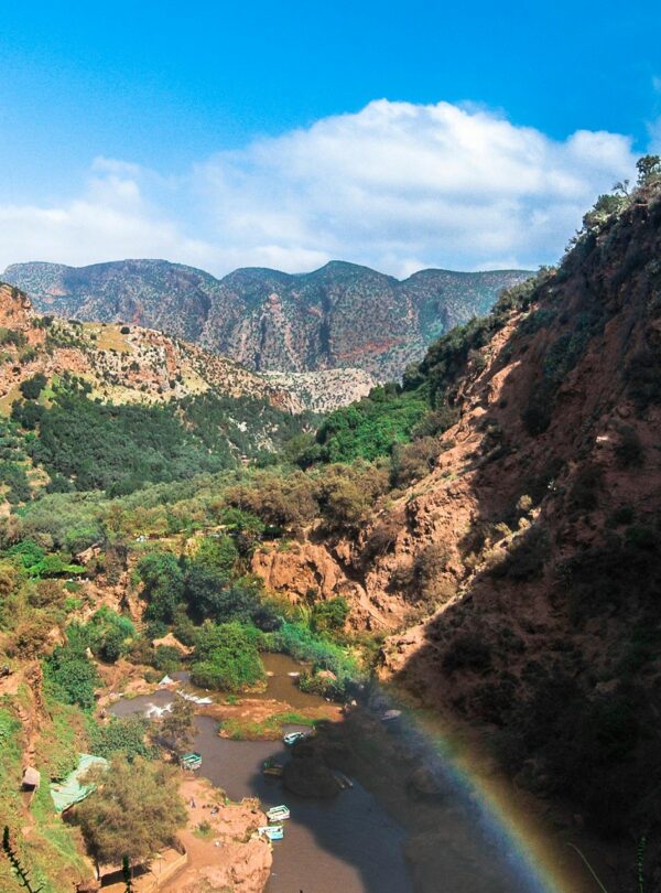 Beautiful canyon landscape with river and rainbow under clear blue sky, perfect for summer travel imagery.