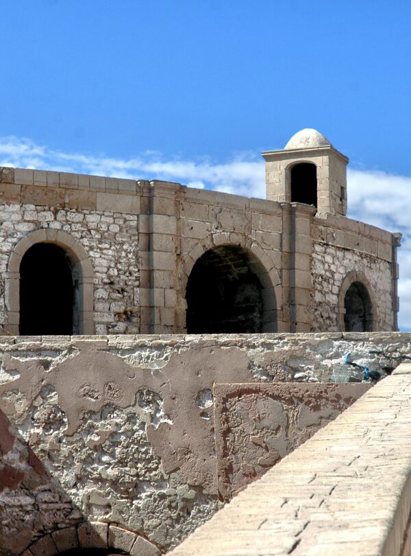 Explore the historic fortress walls of Essaouira, Morocco, against a vibrant blue sky.